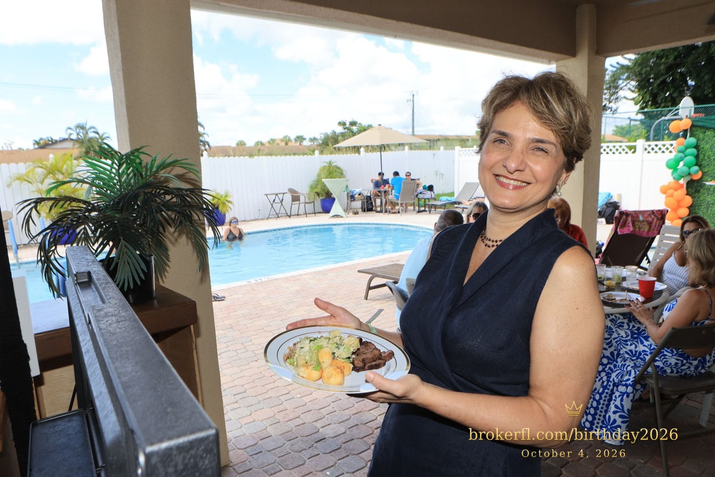 Guest holding a plate beside the poolside patio — Karina Leal's birthday, October 4, 2026.