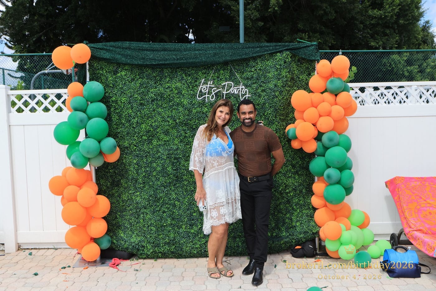 Guests posing in front of the outdoor green and orange balloon backdrop — Karina Leal's birthday, October 4, 2026.
