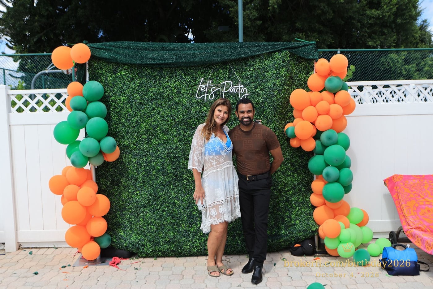 Guests posing in front of the outdoor green and orange balloon backdrop — Karina Leal's birthday, October 4, 2026.
