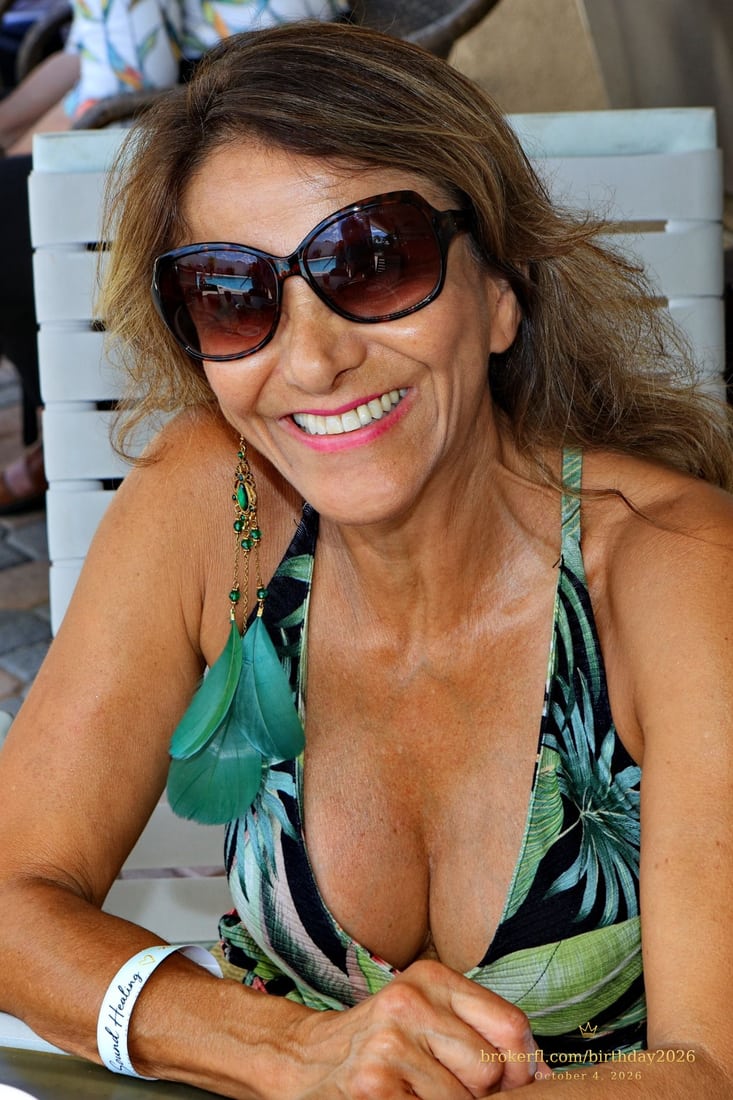 Guest in a tropical print outfit smiling at a patio table — Karina Leal's birthday, October 4, 2026.