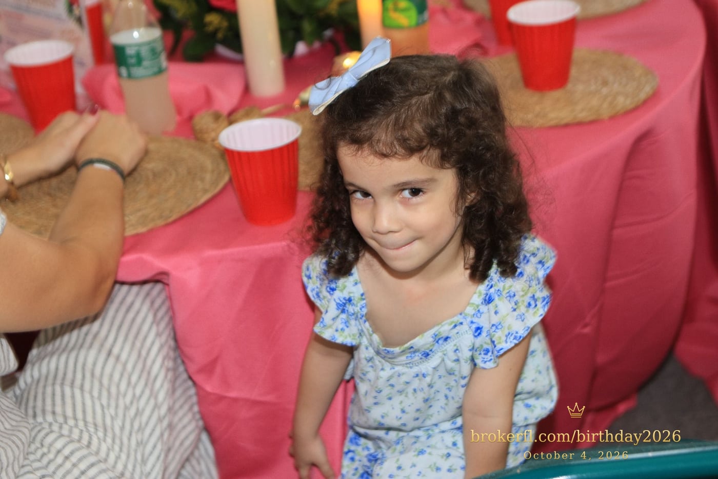 Young guest in a blue dress smiling inside the party room — Karina Leal's birthday, October 4, 2026.