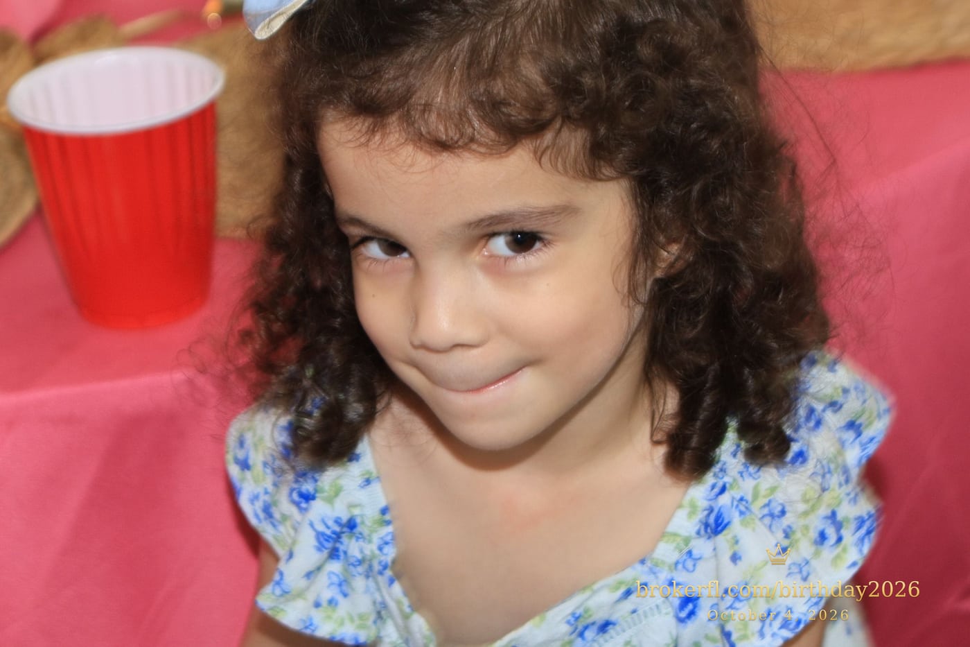 Young guest in a blue dress smiling inside the party room — Karina Leal's birthday, October 4, 2026.