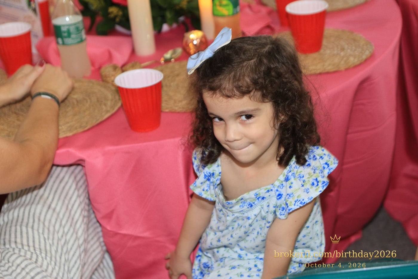 Young guest in a blue dress smiling inside the party room — Karina Leal's birthday, October 4, 2026.