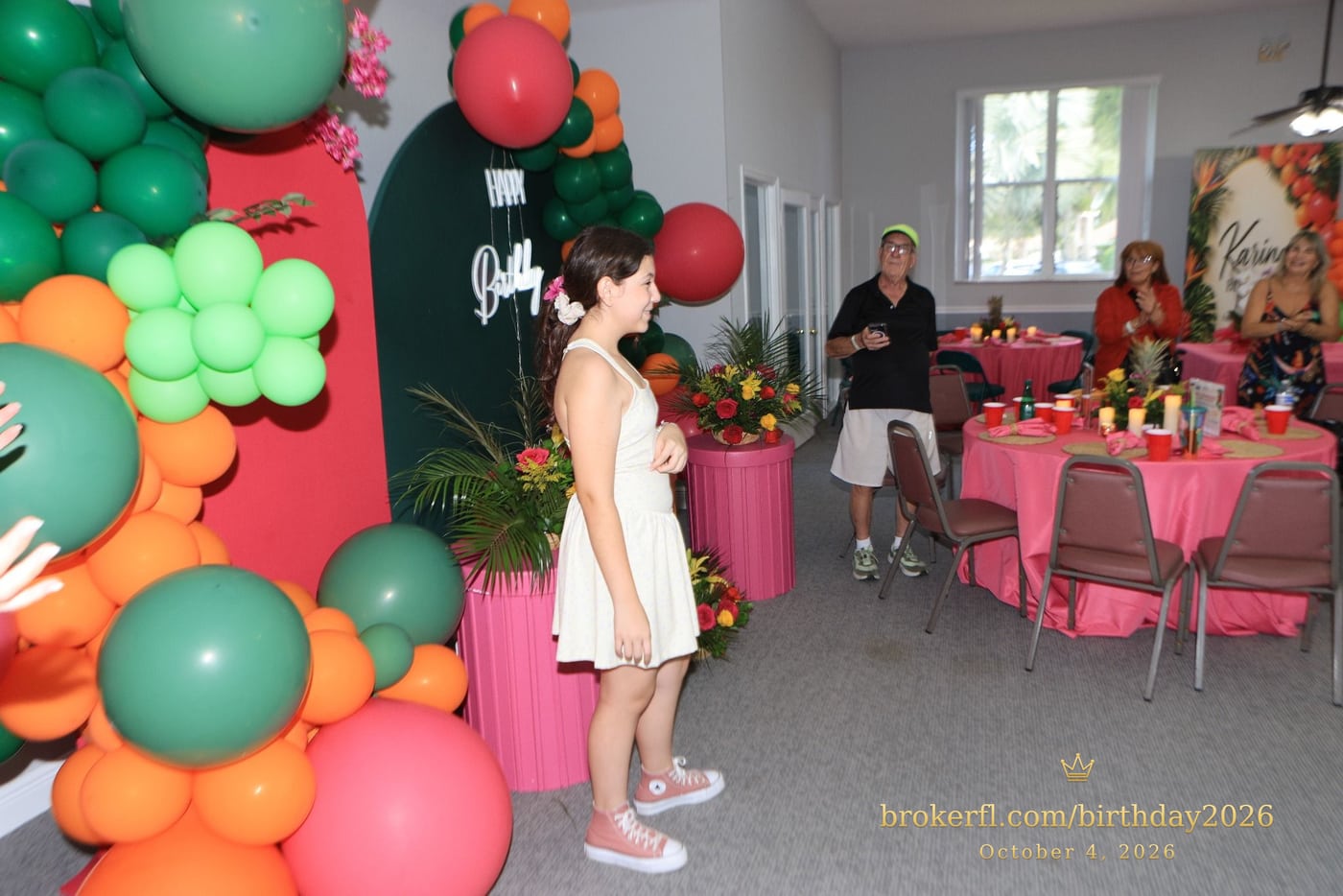 Guest in a cream dress beside the birthday cake display — Karina Leal's birthday, October 4, 2026.