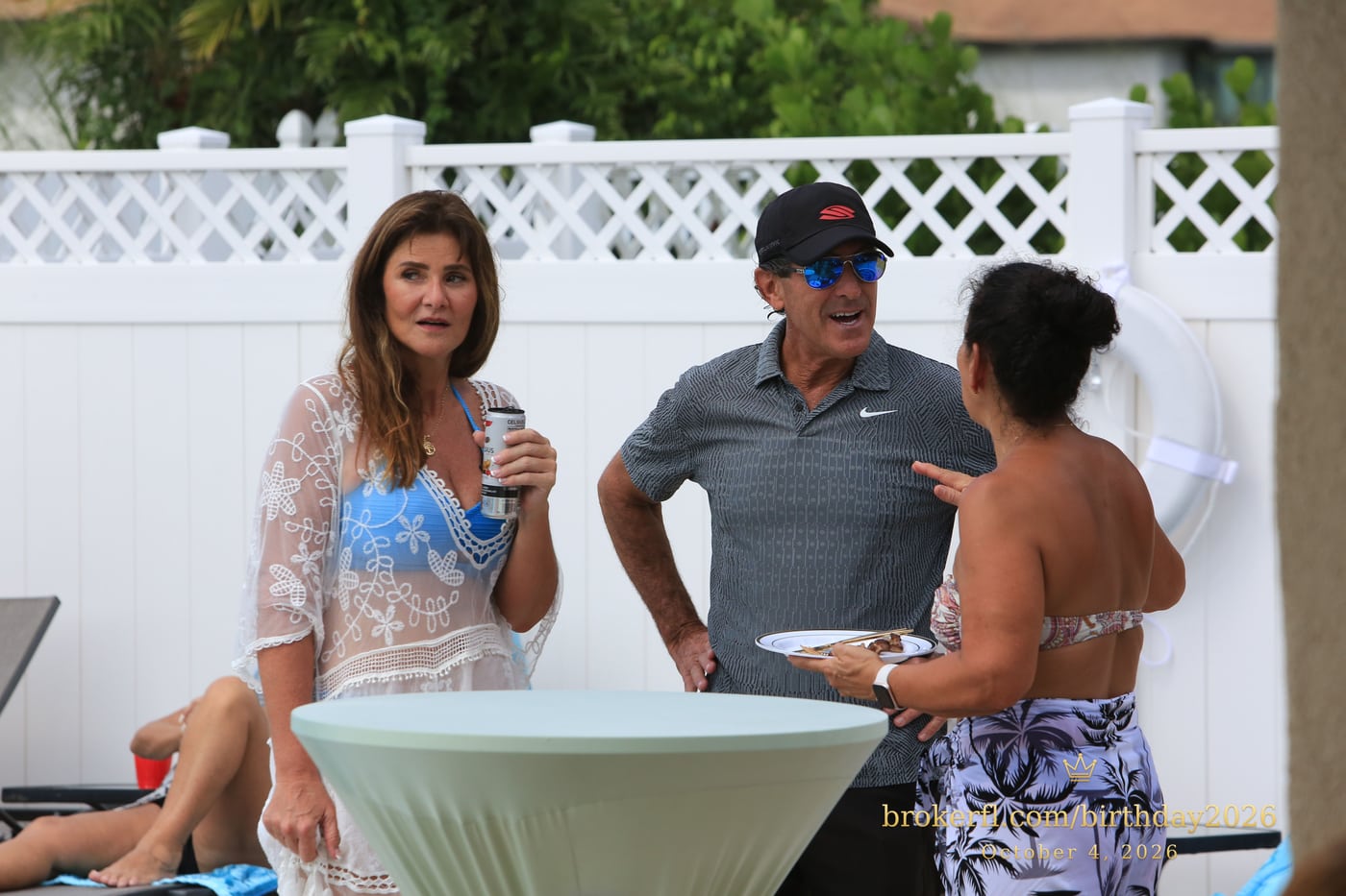 Guests chatting around a table beside the pool — Karina Leal's birthday, October 4, 2026.