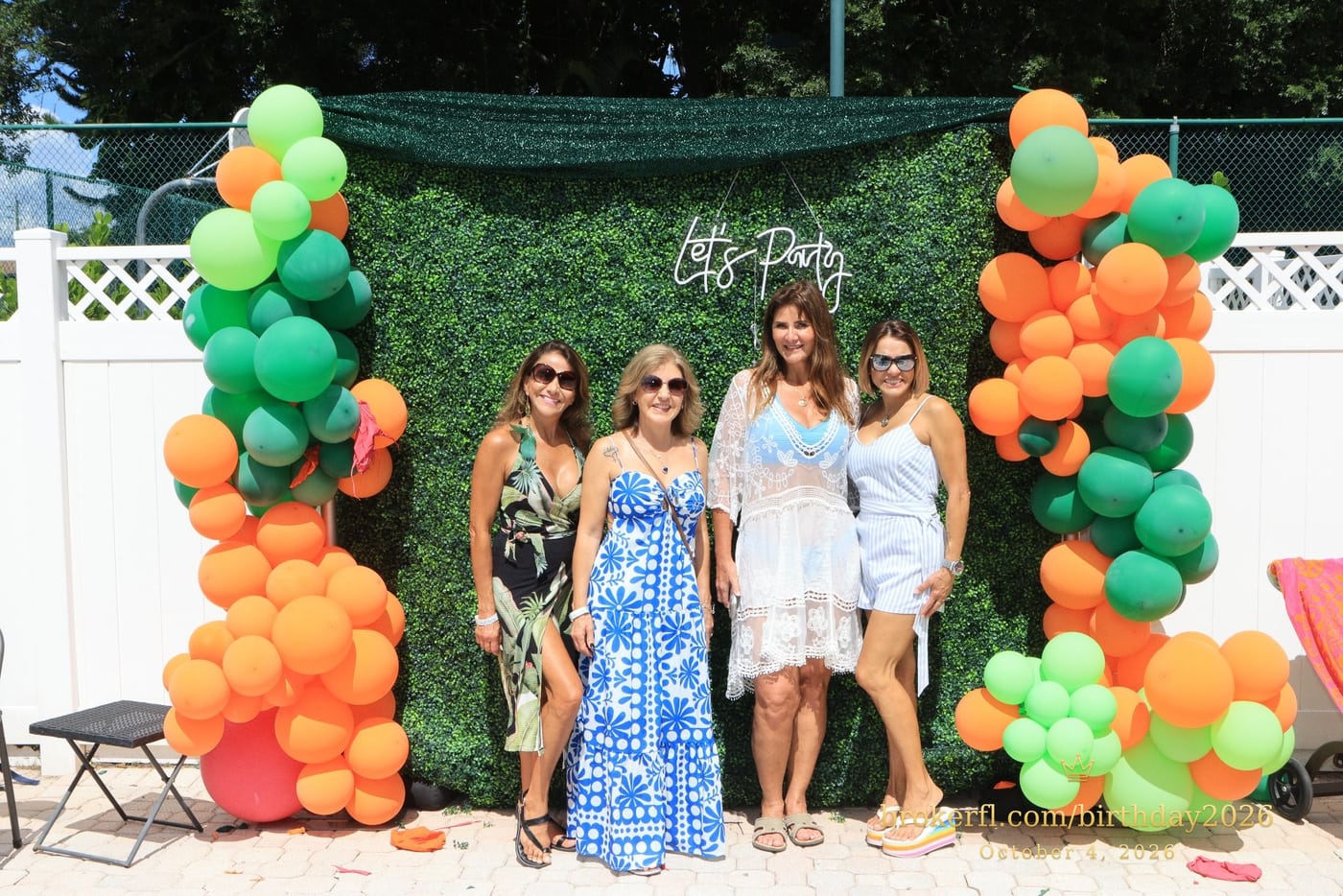Guests posing in front of the outdoor green and orange balloon backdrop — Karina Leal's birthday, October 4, 2026.