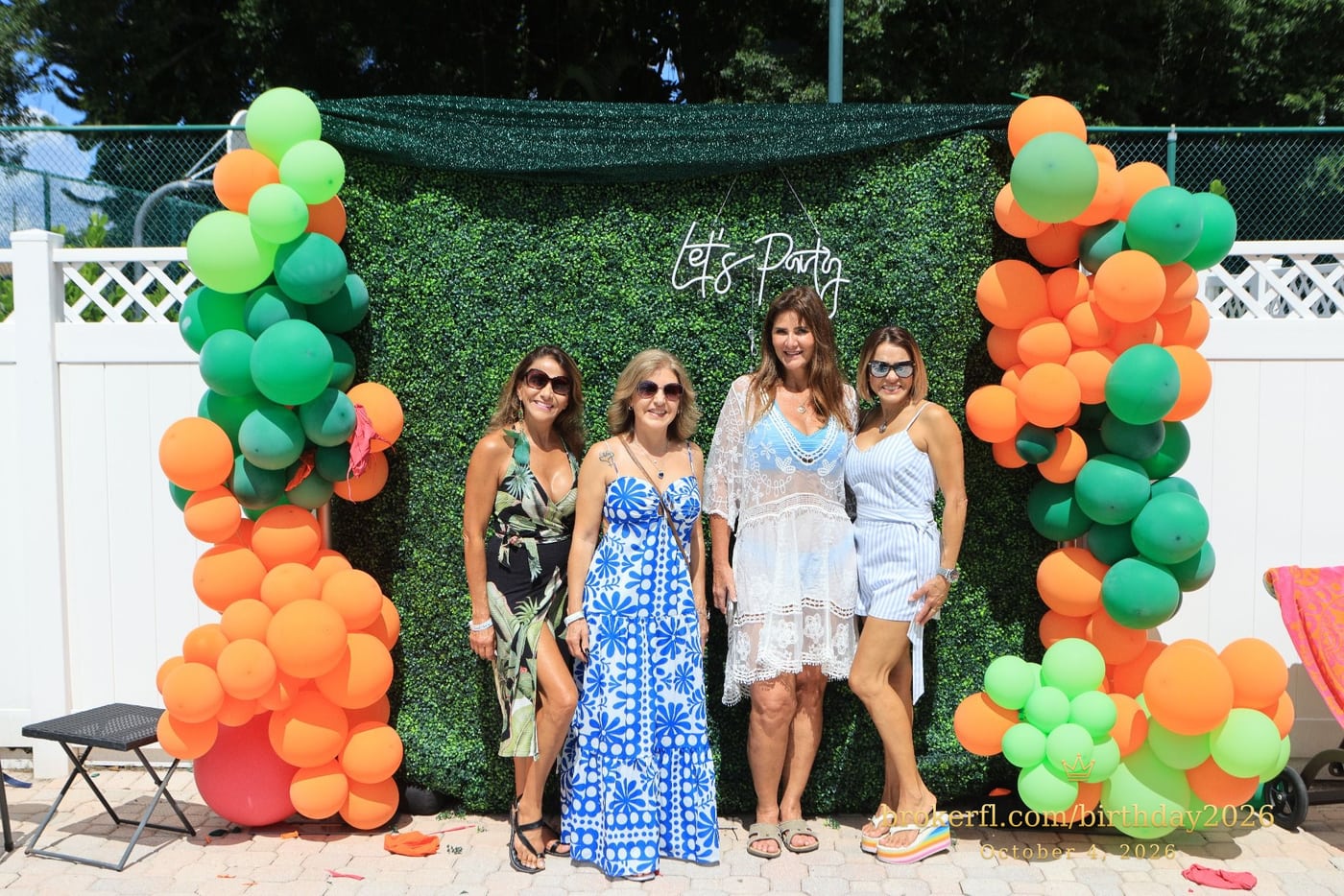 Guests posing in front of the outdoor green and orange balloon backdrop — Karina Leal's birthday, October 4, 2026.