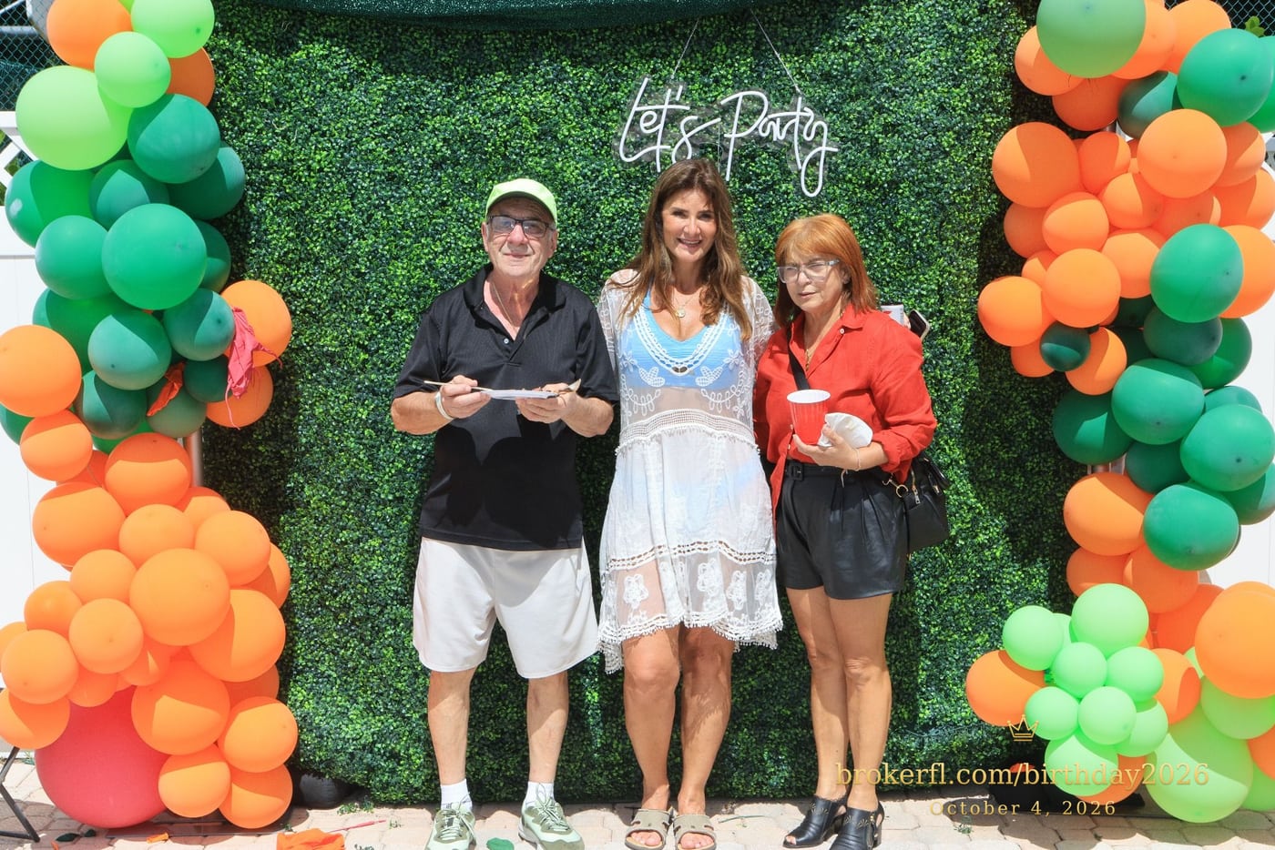 Guests posing in front of the outdoor green and orange balloon backdrop — Karina Leal's birthday, October 4, 2026.