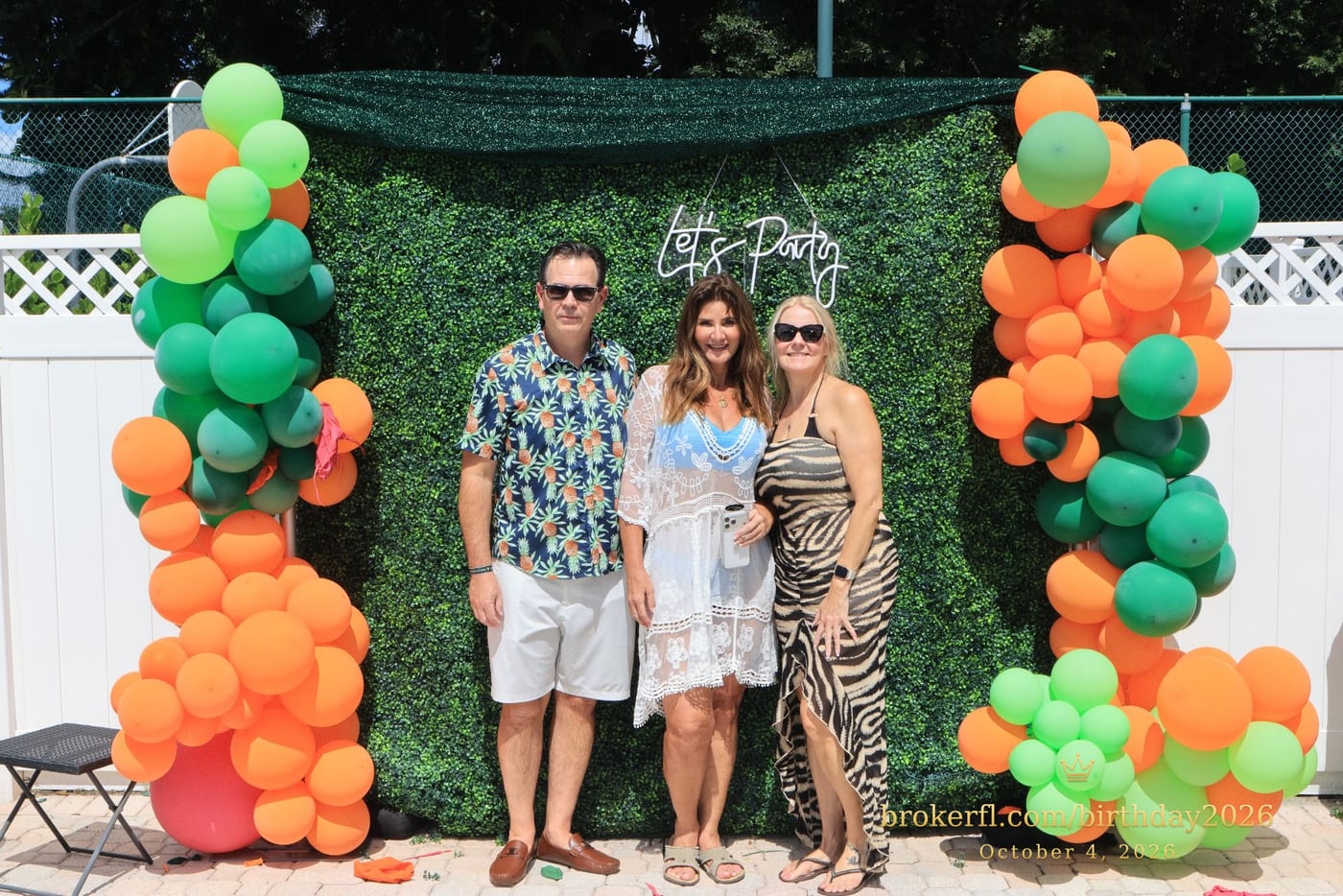 Guests posing in front of the outdoor green and orange balloon backdrop — Karina Leal's birthday, October 4, 2026.