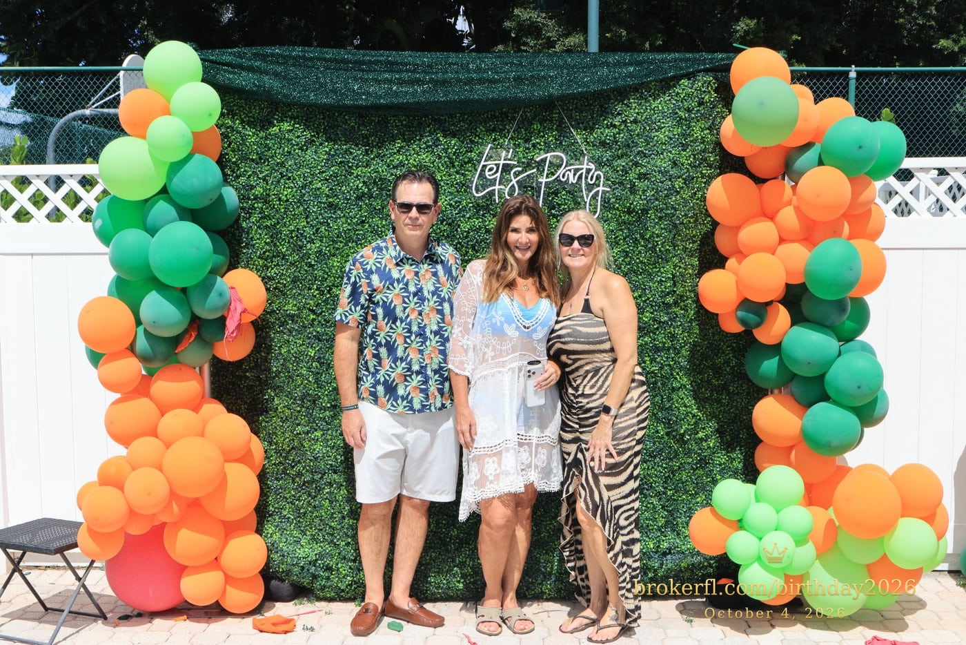 Guests posing in front of the outdoor green and orange balloon backdrop — Karina Leal's birthday, October 4, 2026.
